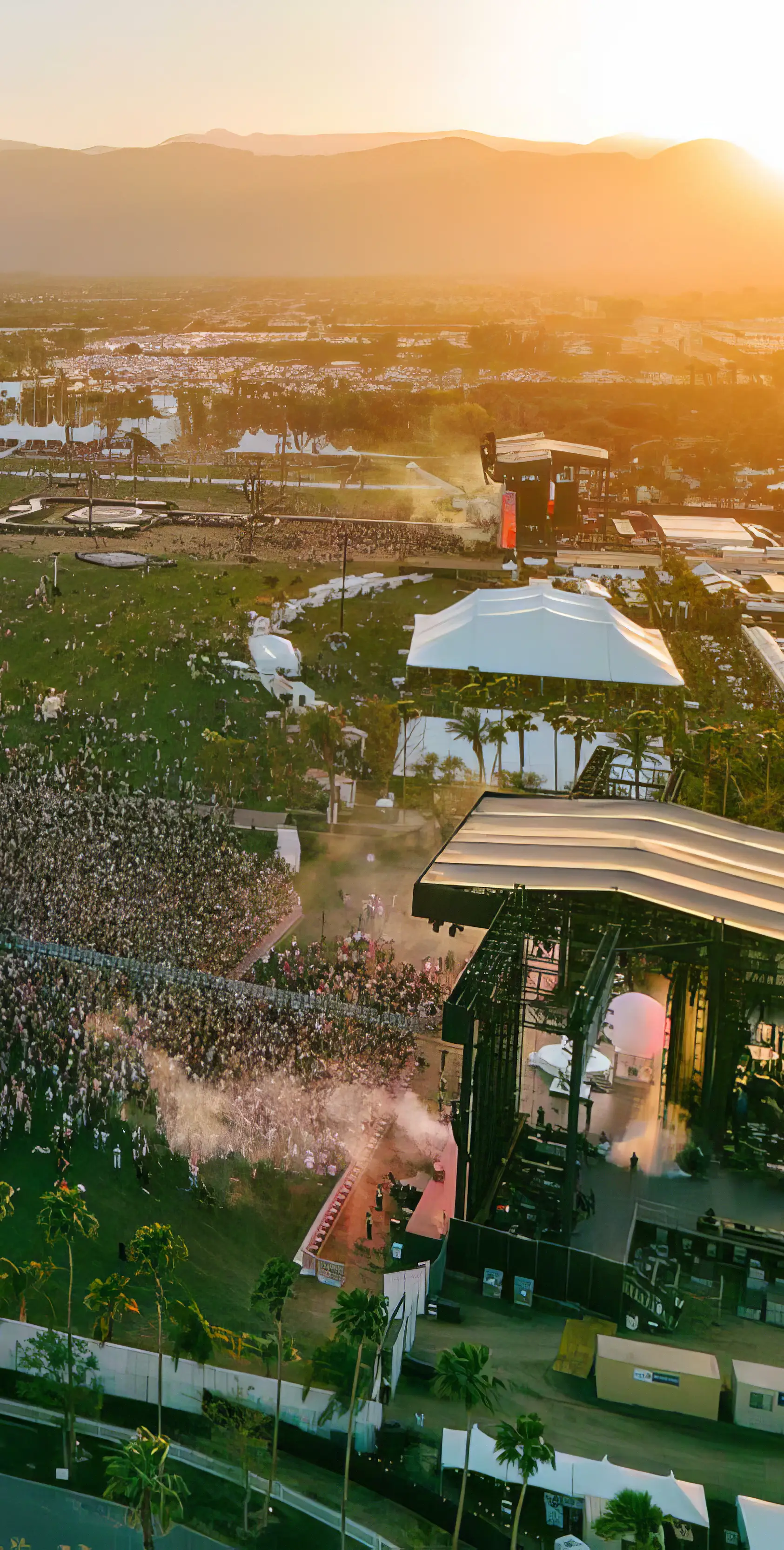An image of large crowds watching on-stage performances at Coachella festival, while the sun sets over Indio, California.